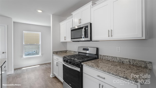 kitchen featuring light stone countertops, white cabinets, stainless steel appliances, and light hardwood / wood-style floors