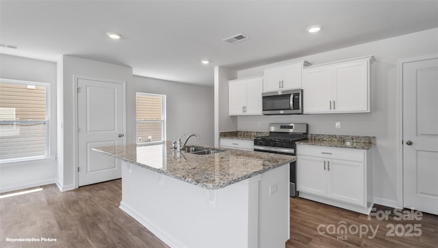 kitchen featuring white cabinetry, a kitchen island with sink, sink, and appliances with stainless steel finishes