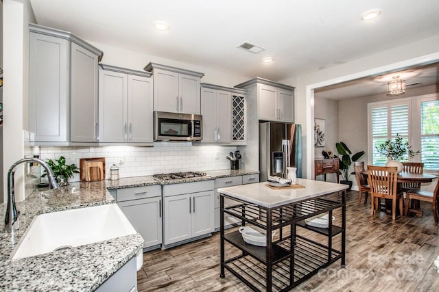 kitchen with stainless steel appliances, backsplash, wood-type flooring, and sink