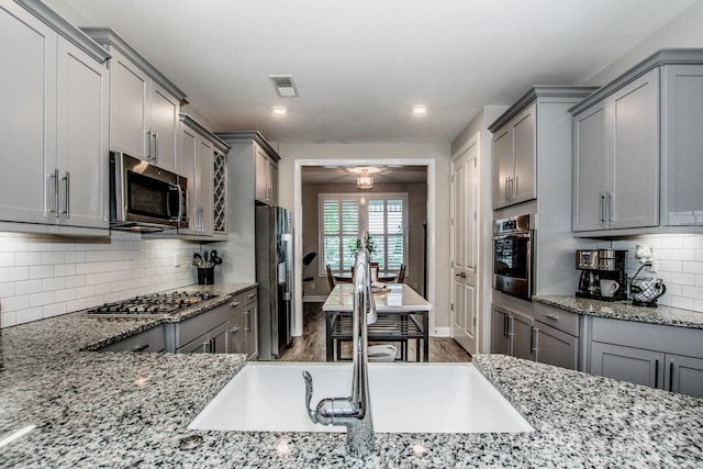 kitchen featuring appliances with stainless steel finishes, backsplash, dark hardwood / wood-style floors, and light stone counters