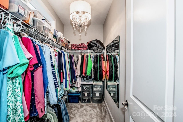 spacious closet featuring carpet floors and an inviting chandelier