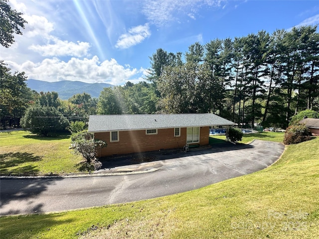 view of side of property featuring a yard, brick siding, a mountain view, and driveway