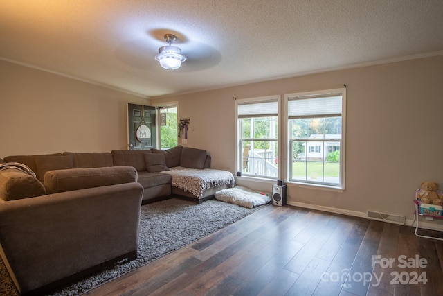 living area featuring visible vents, ornamental molding, a textured ceiling, baseboards, and dark wood-style flooring