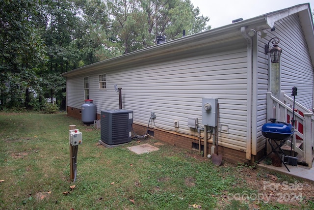 view of side of property featuring a yard and central AC