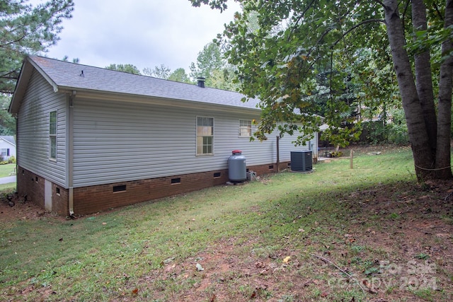 back of property with central air condition unit and a lawn