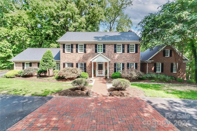 colonial-style house featuring a front yard