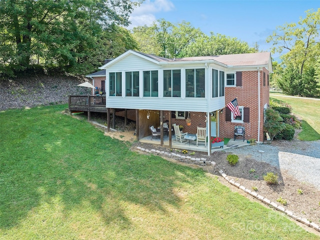 rear view of property with a yard, a sunroom, a wooden deck, and a patio area