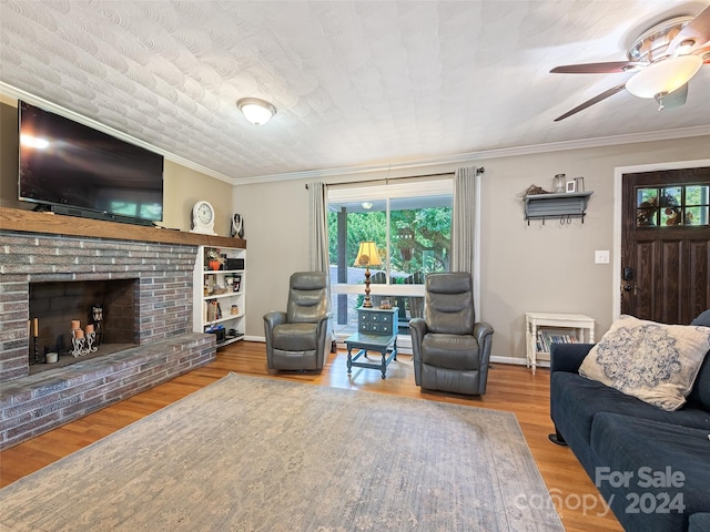 living room featuring wood-type flooring, plenty of natural light, a fireplace, and crown molding