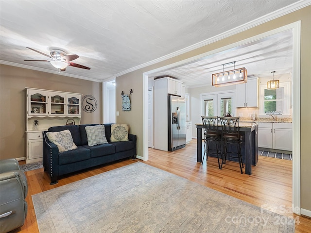 living room with ceiling fan, ornamental molding, french doors, and light hardwood / wood-style floors