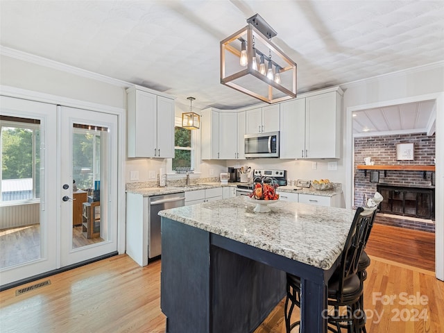 kitchen with white cabinets, appliances with stainless steel finishes, decorative light fixtures, crown molding, and french doors