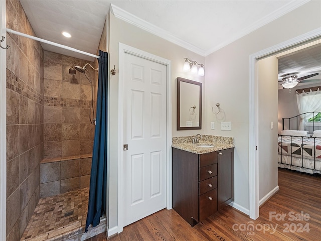 bathroom with hardwood / wood-style flooring, walk in shower, crown molding, ceiling fan, and vanity