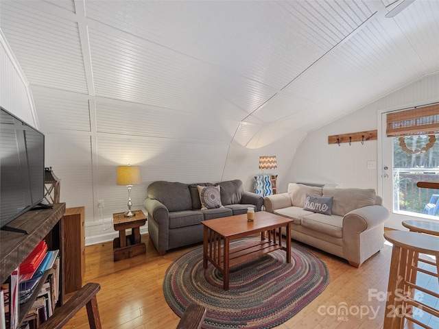 living room with light hardwood / wood-style flooring, lofted ceiling, and wood walls