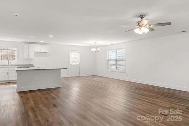 unfurnished living room featuring dark hardwood / wood-style floors, sink, and ceiling fan with notable chandelier