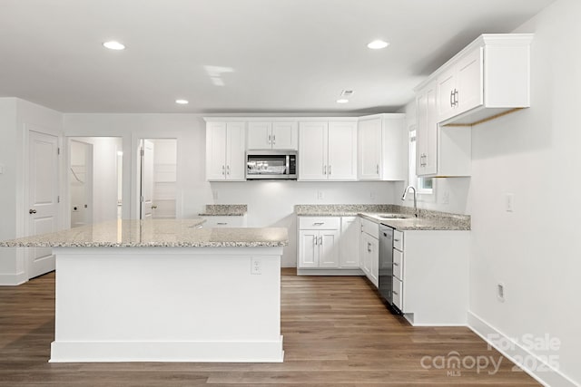 kitchen with a center island, dark wood-type flooring, white cabinets, light stone countertops, and stainless steel appliances