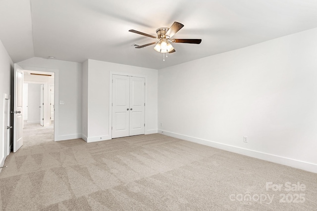 unfurnished bedroom with ceiling fan, light colored carpet, lofted ceiling, and a closet