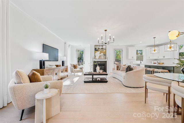 living room featuring light hardwood / wood-style flooring, a wealth of natural light, and a notable chandelier