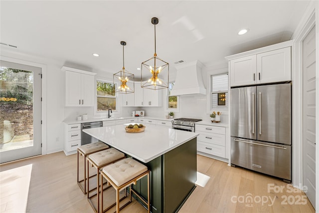 kitchen with pendant lighting, premium range hood, a kitchen island, a kitchen bar, and stainless steel appliances