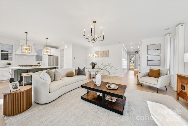 living room featuring light wood-type flooring, crown molding, and an inviting chandelier