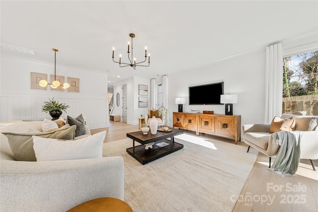 living room with a chandelier, light hardwood / wood-style floors, and ornamental molding