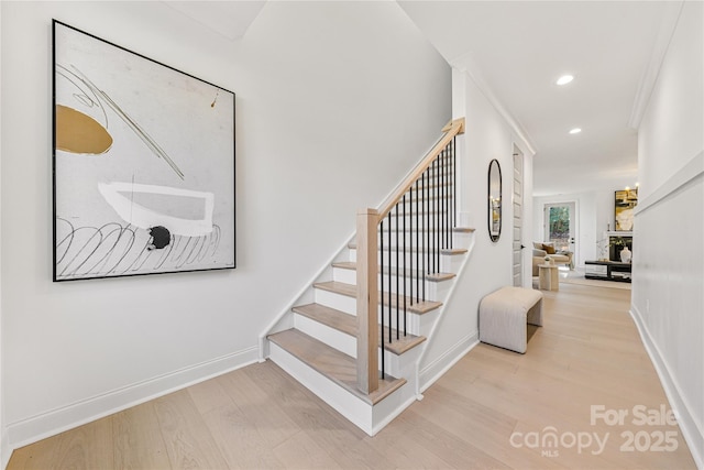 staircase with hardwood / wood-style floors and crown molding