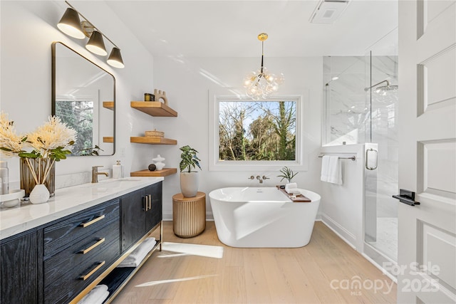 bathroom with hardwood / wood-style flooring, a notable chandelier, separate shower and tub, and vanity