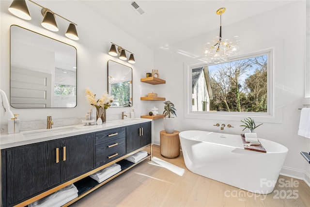 bathroom with a notable chandelier, a tub to relax in, and vanity