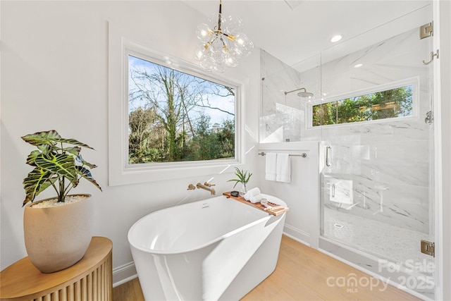 bathroom featuring plus walk in shower, wood-type flooring, and a chandelier