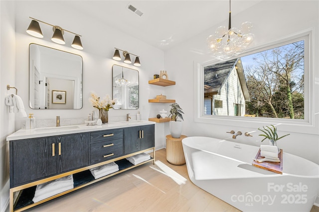 bathroom with vanity, hardwood / wood-style flooring, a tub, and a notable chandelier