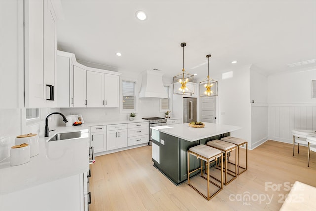 kitchen with white cabinets, a center island, sink, and premium range hood