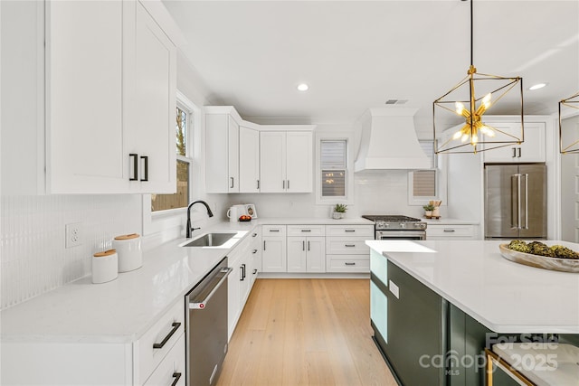 kitchen with white cabinetry, sink, pendant lighting, appliances with stainless steel finishes, and custom exhaust hood