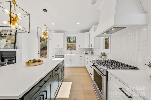 kitchen featuring stainless steel range with gas cooktop, a center island, white cabinets, and sink