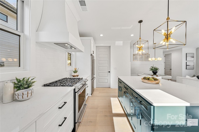 kitchen featuring custom range hood, blue cabinets, pendant lighting, high quality appliances, and white cabinets