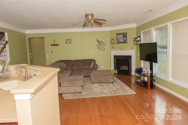 living room with hardwood / wood-style flooring, ceiling fan, crown molding, and sink