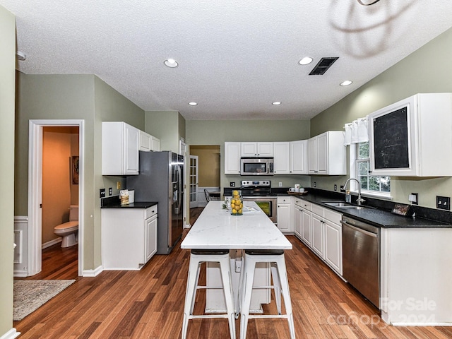 kitchen featuring appliances with stainless steel finishes, white cabinetry, a center island, and sink