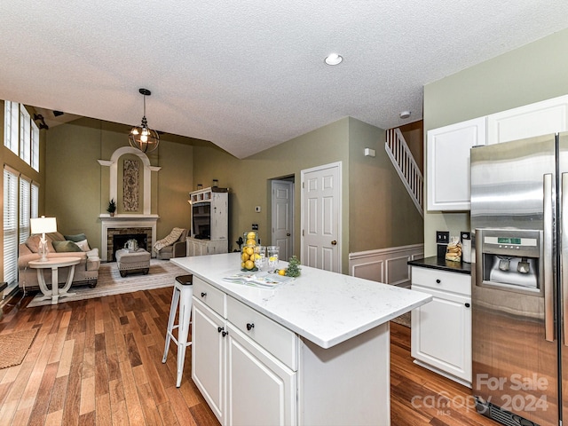 kitchen featuring white cabinets, hanging light fixtures, a kitchen island, dark wood-type flooring, and stainless steel fridge with ice dispenser