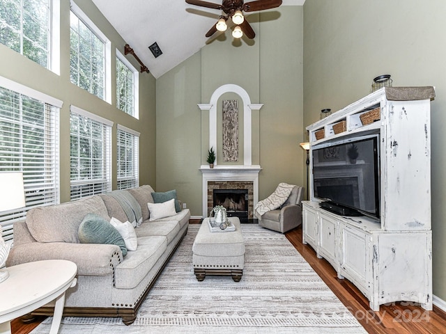 living room featuring ceiling fan, wood-type flooring, a fireplace, and high vaulted ceiling