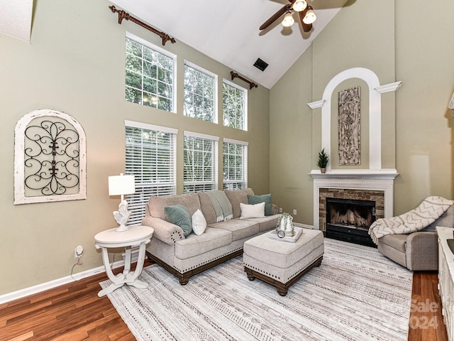 living room featuring ceiling fan, a stone fireplace, hardwood / wood-style flooring, and high vaulted ceiling