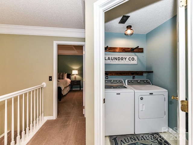 laundry area featuring light carpet, separate washer and dryer, a textured ceiling, and ornamental molding