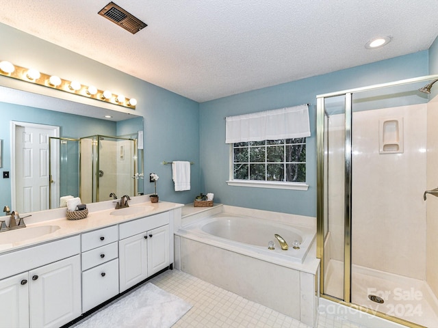 bathroom with a textured ceiling, shower with separate bathtub, vanity, and tile patterned floors