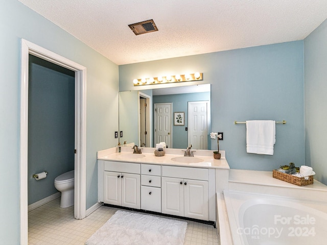 bathroom featuring a textured ceiling, a bath, vanity, and toilet