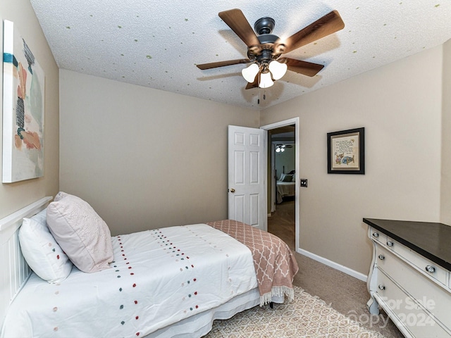 carpeted bedroom with ceiling fan and a textured ceiling