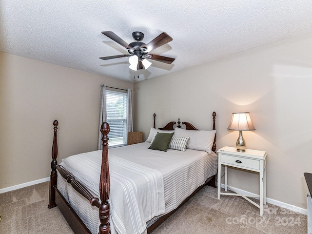 bedroom with ceiling fan, light colored carpet, and a textured ceiling