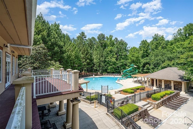 view of swimming pool with a water slide and a patio area