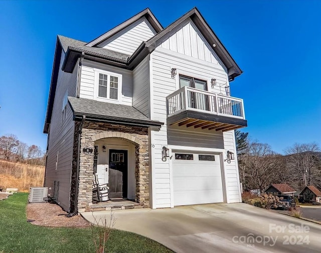 view of front of house featuring a balcony, central AC unit, and a garage