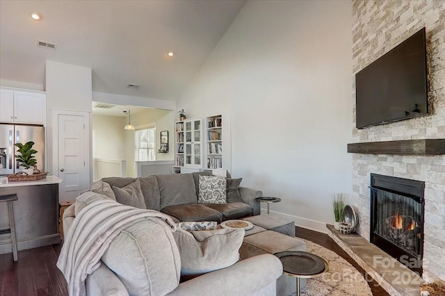 living room featuring a stone fireplace, dark wood-type flooring, and high vaulted ceiling