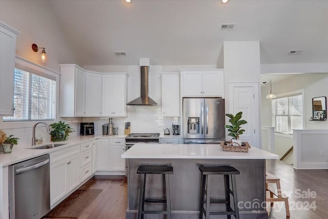 kitchen with wall chimney exhaust hood, white cabinetry, sink, and appliances with stainless steel finishes