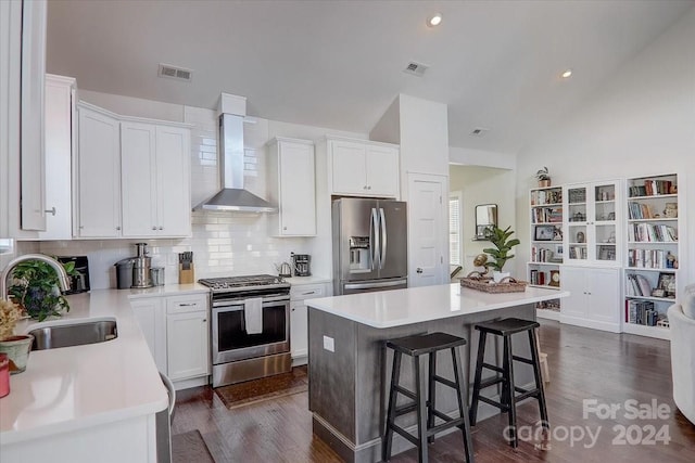 kitchen featuring sink, wall chimney exhaust hood, vaulted ceiling, a kitchen island, and appliances with stainless steel finishes