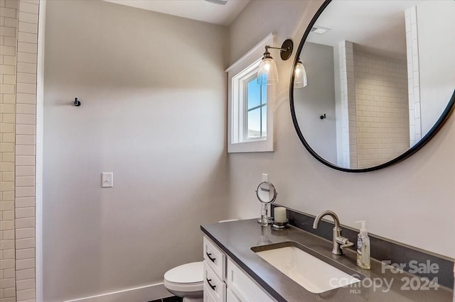 bathroom featuring vanity, toilet, and a tile shower