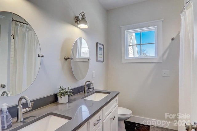 bathroom with tile patterned floors, plenty of natural light, vanity, and toilet