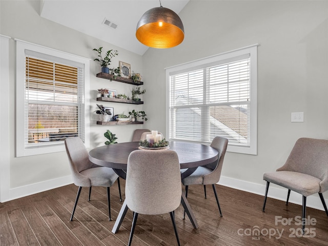 dining room with dark wood-type flooring, vaulted ceiling, and a wealth of natural light